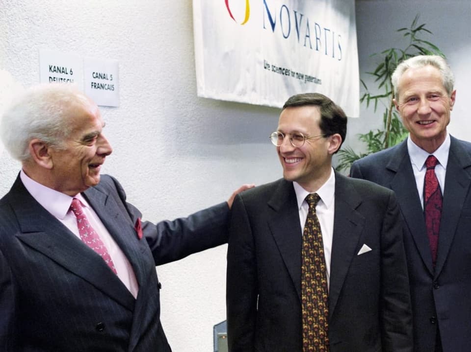 Drei Männer vor Novartisschild